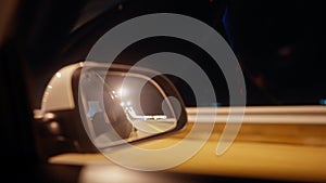 View side mirror car driving fast along night road in dark illuminated lanterns