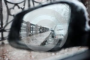 View in the side rearview mirror of the car in inclement weather