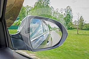 A view in the side view mirror. Mirror rear car. Reflection of the road