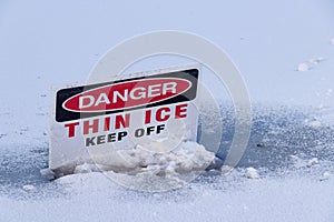 View of sign on a frozen Lost Lagoon lake in Vancouver. `Danger, Thin Ice, Keep off`.