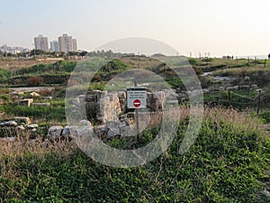 View of the sign with the inscription Danger! and ancient walls in Tel Shikmona in Israel.