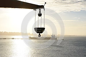 View on the silhouette of tanker vessel under the sun along discharging pipe.