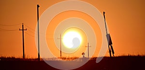 View of the silhouettes of electricity poles during sunset