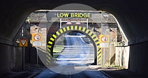 A view of a single lane tunnel, with yellow and black warning stripes, and lettering which states Low Bridge