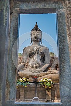 View of Sitting Buddha statue through stone door in the Ancient temple Thailand