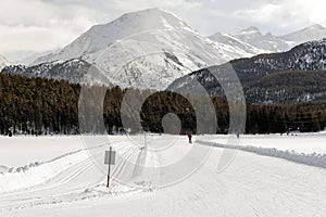 A view of ski piste and people ski and walk in the snow covered landscape and mountains in the alps switzerland in winter