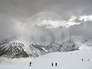 A view of a ski slope with mountain tops and a light passing through cloids in the background photo