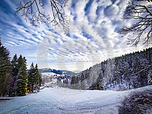 View of ski slope in Ore Mountains, Czech Republic. In the background is the mountain Plesivec. There are beautiful white clouds