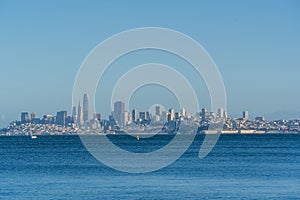 View of skyline of San Francisco, city buildings, skyscrapers by the sea under blue sky