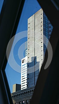 View of a skyscraper against a clear blue sky from a train window