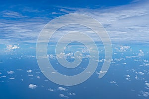 View of small abstract white cloud with bright blue sky horizon and vast sea ocean background from above flying airplane window