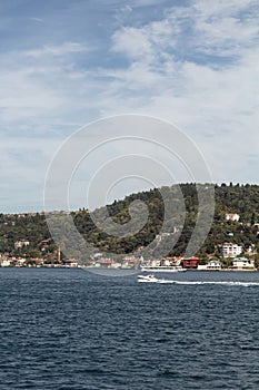 View of a small boat passing on Bosphorus and Asian side of Istanbul. It is a sunny summer day.