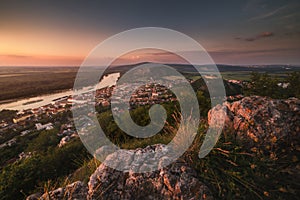 View of Small City and River with Rocks in Foreground at Sunset