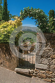 View of small garden behind iron gate and stone wall in the village of MÃÂ©nerbes.