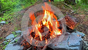 View of a small hot fire. Bright red and yellow sparks and flames. Wooden logs smoke and burn