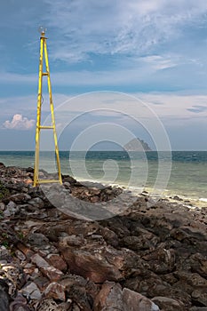 View on a small island from the rocky shore with a lighthouse in Thailand
