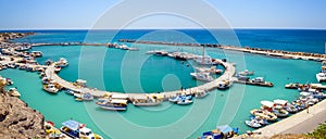 View on small port and fishing boats parked near pier of Vlychada town on Santorini island