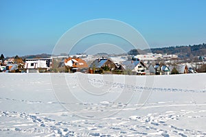 View of small rural town in Odenwald in Germany with clearing covered in snow during winter