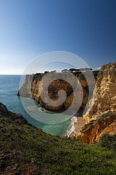 View of a small secluded beach surrounded by cliffs in Algarve