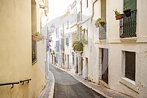 View of small street with white houses and flowers in the traditional spanish town of Sitges in the Catalonia region