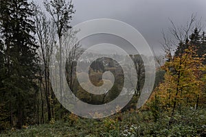 View of a small town in the valley of the river Sazava over the trees crowns under the dark clouds