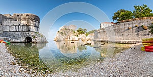 View of small water bay near old city of Dubrovnik. Ancient fort Lovrijenac near small harbor with boats. Sunny day