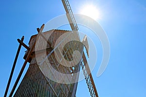 View of a small wooden windmill against a blue sky background