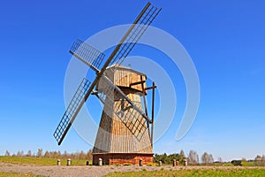 View of a small wooden windmill against a blue sky background