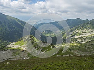 Pohľad zo Smutného sedla na horskú dolinu Smutná dolina so skalnými balvanmi, chodníkom, kosodrevinou a zeleňou