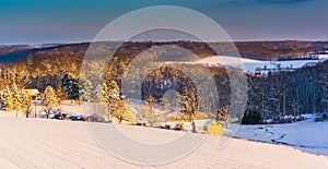 View of snow covered farm fields and rolling hills at sunset in