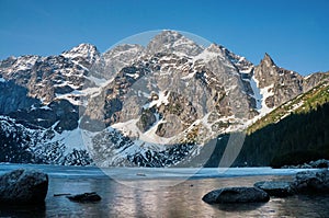 view of snow covered mountain peaks over lake water, Morskie Oko, Sea Eye, Tatra National