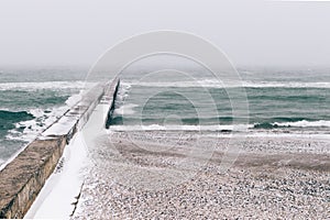 View of snow-covered pier and beach during blizzard