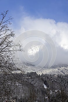 View of the snow peaks of the Alps mountains above the city, clouds against blue sky, Innsbruck, Austria