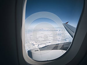 View of snowy landscape through plane porthole