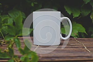A solo blank white coffee mug on the wooden table in the garden