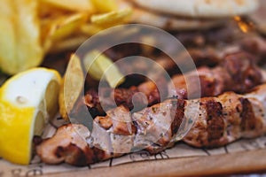 View of Souvlaki on a plate - traditional greek cuisine dish with grilled bbq chicken with french fries and tzatziki sauce served