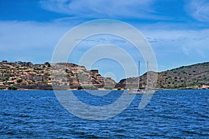 View of Spinalonga island and Venetian fortress, Crete, Greece, and yacht floating on clear summer day