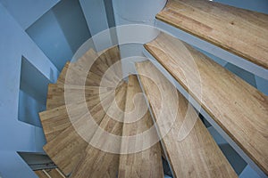 View of spiral wooden staircase with blue wall.