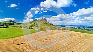 Pohled na Spišský hrad a pole s kulatými balíky na Slovensku
