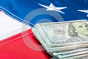 View of a stack of money lying on the flag of the United States of America