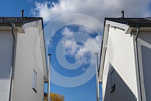 View of stainless steel chimneys between two houses in front of blue sky