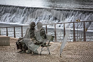 View at the statue of two men seat on bench, artistic personalities on Tomar city