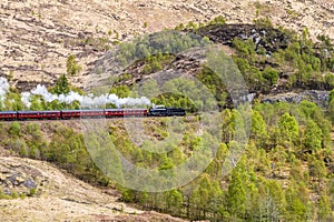 A view of a steam train leaving the valley at Glenfinnan, Scotland