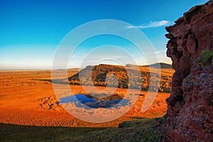 View of the steppe mountains and the lake from the cliff during sunset