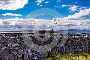 View of a stone fences on the island of Inis Oirr with the Plassey shipwreck and the Cliffs of Moher in the background