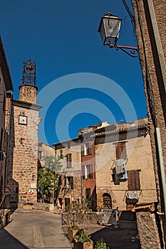 View of stone houses and tower in a street under blue sky at Les Arcs-sur-Argens.