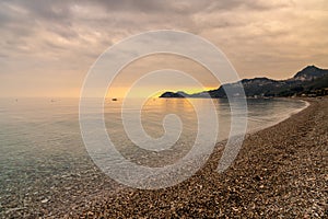 view of the stone pebble beach and clear water at Letojanni on Sicily at sunsest