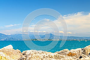 View from stone pier mole of Garda Lake azure water with Monte Baldo mountain range and Sirmione peninsula