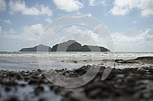 View of the stormed sea and island mountain among the sea.little rock beach on foreground.