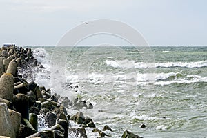View of the stormy sea, waves splashing against the concrete pier
